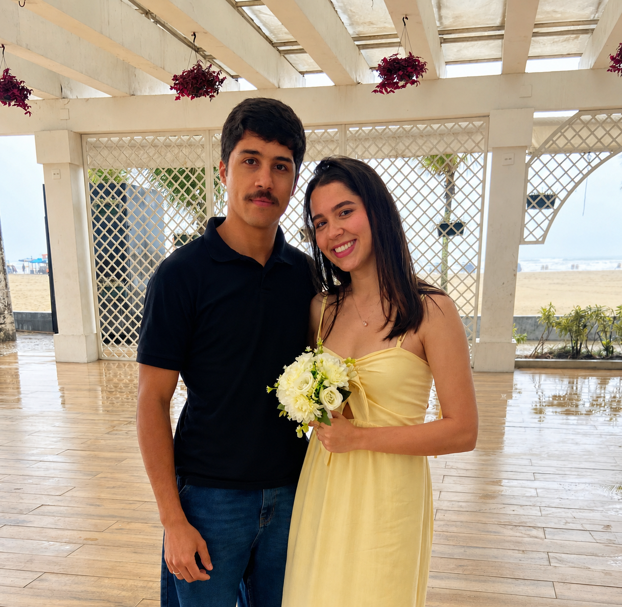 O casal com um buquê de flores em um quiosque à beira-mar