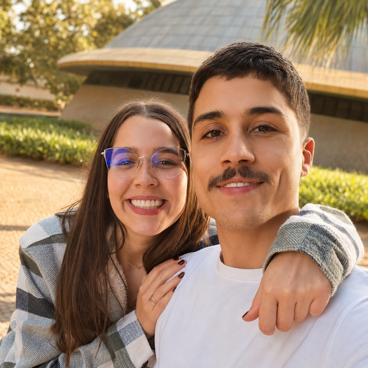 Beatriz e Bruno sorrindo juntos ao ar livre no fim de tarde